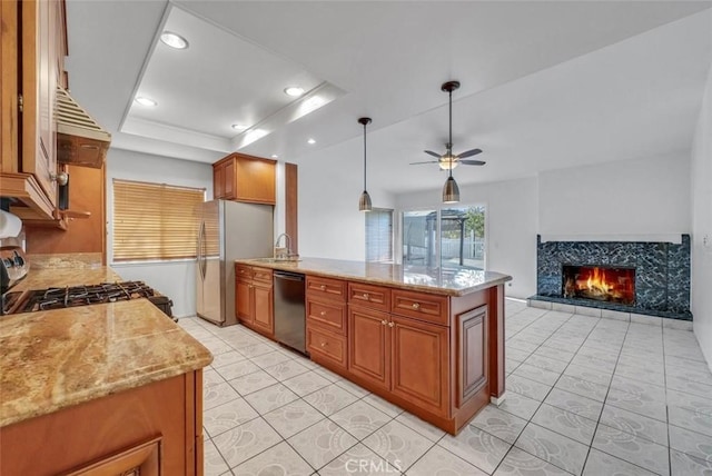 kitchen featuring pendant lighting, appliances with stainless steel finishes, a high end fireplace, ceiling fan, and light stone counters