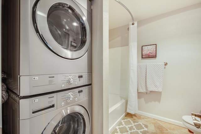 washroom with stacked washer / drying machine and light tile patterned floors