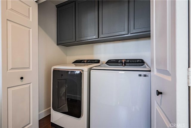 clothes washing area featuring separate washer and dryer, cabinets, and dark wood-type flooring