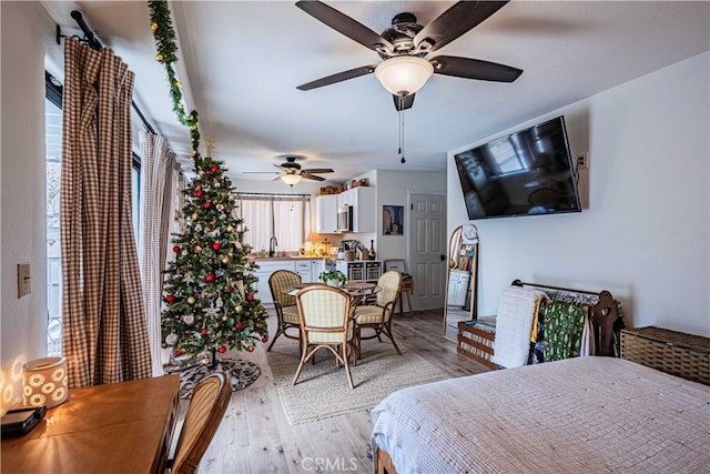 bedroom with ceiling fan, sink, and light hardwood / wood-style flooring