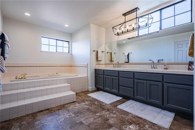 bathroom with vanity and tiled tub