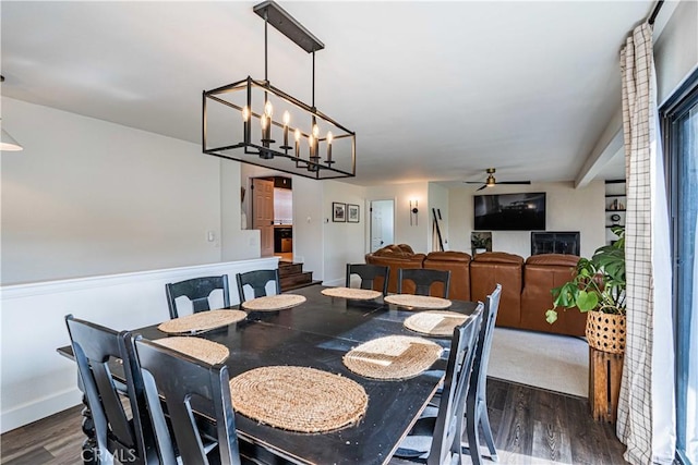 dining space with beamed ceiling, ceiling fan with notable chandelier, and dark hardwood / wood-style floors