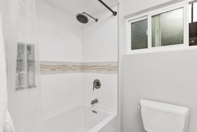 bathroom featuring tiled shower / bath combo and toilet