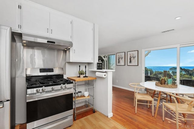 kitchen with stainless steel range with gas cooktop, white cabinetry, and light hardwood / wood-style flooring