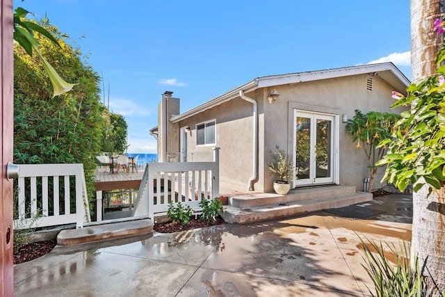 back of property with a wooden deck and a patio area