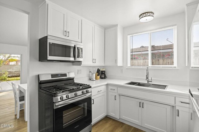 kitchen with white cabinets, stainless steel appliances, light hardwood / wood-style floors, and sink