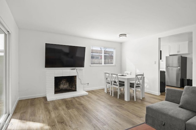 living room with a brick fireplace and light hardwood / wood-style flooring