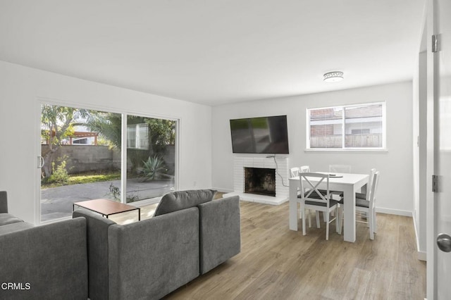 living room featuring a brick fireplace, a wealth of natural light, and light wood-type flooring