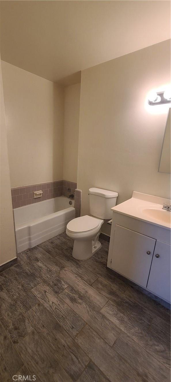 bathroom with toilet, vanity, a bathtub, and hardwood / wood-style floors