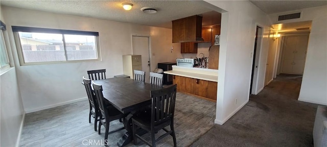 dining space with a textured ceiling and hardwood / wood-style floors