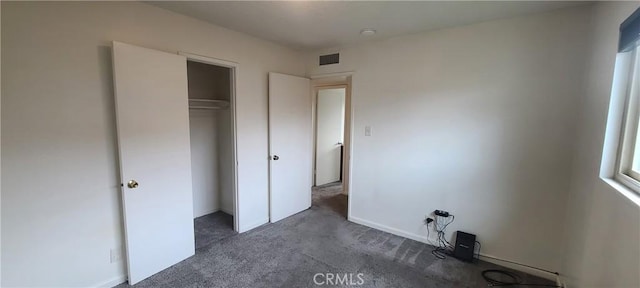 unfurnished bedroom with a closet and dark colored carpet