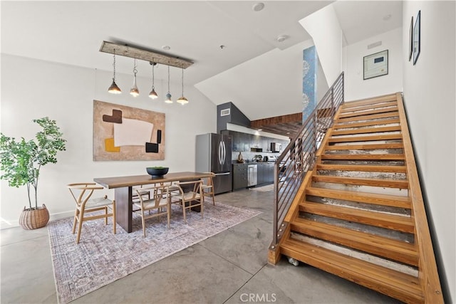 dining area with stairs, lofted ceiling, and concrete flooring