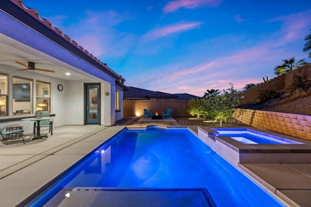 pool at dusk featuring a patio area, an in ground hot tub, and ceiling fan