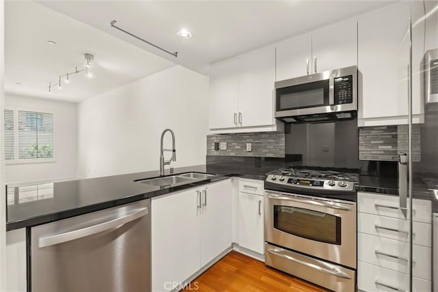 kitchen featuring backsplash, sink, white cabinetry, and stainless steel appliances