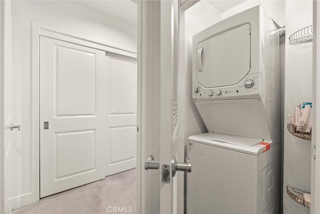 clothes washing area with light colored carpet and stacked washing maching and dryer