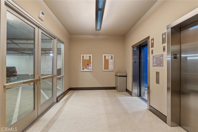 hallway featuring light carpet and elevator