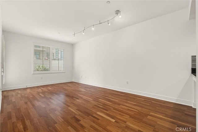 empty room featuring track lighting and dark hardwood / wood-style floors