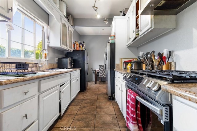 kitchen with dark tile patterned flooring, white cabinetry, stainless steel appliances, and exhaust hood