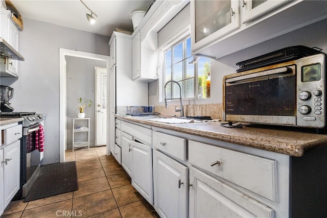 kitchen featuring dark tile patterned floors, white cabinetry, and appliances with stainless steel finishes