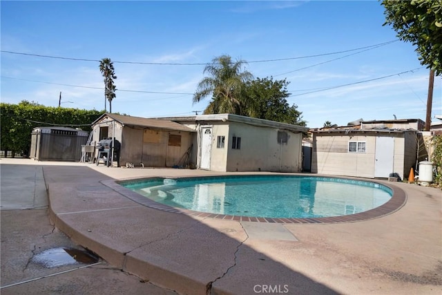 view of pool with a patio, a storage unit, and a grill