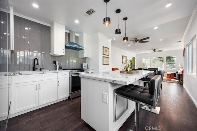 kitchen featuring visible vents, wall chimney range hood, stainless steel electric range oven, decorative backsplash, and a sink