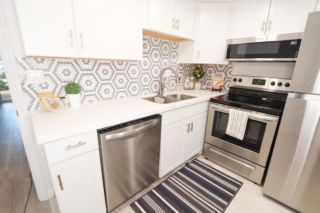 kitchen with stainless steel appliances, white cabinets, sink, and tasteful backsplash