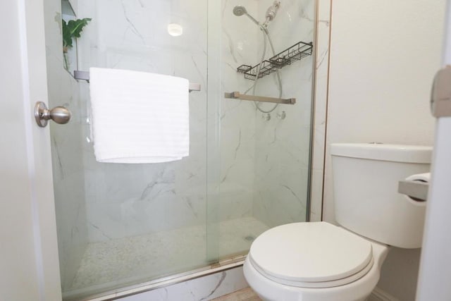 bathroom with a shower with door and toilet