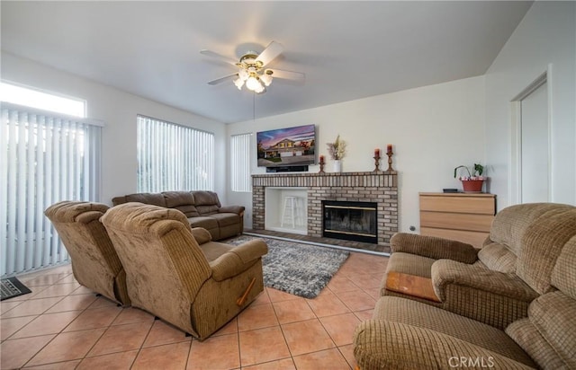 tiled living room featuring a brick fireplace and ceiling fan