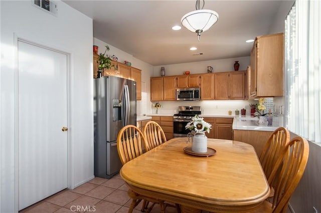 kitchen with pendant lighting, light tile patterned floors, and stainless steel appliances