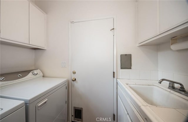 washroom featuring washer and dryer, cabinets, and sink