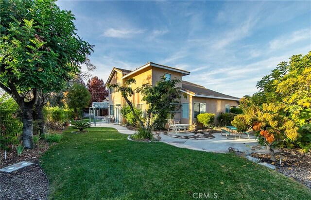 back of property with a yard and a patio