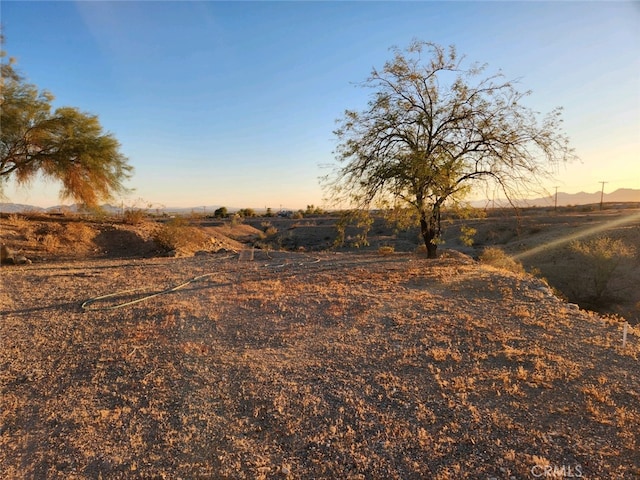 yard at dusk featuring a rural view