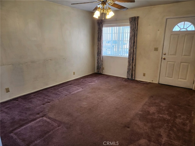 foyer entrance with ceiling fan and dark carpet