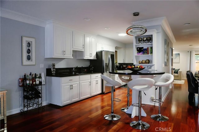 kitchen featuring white cabinetry, a breakfast bar, dark hardwood / wood-style floors, and ornamental molding