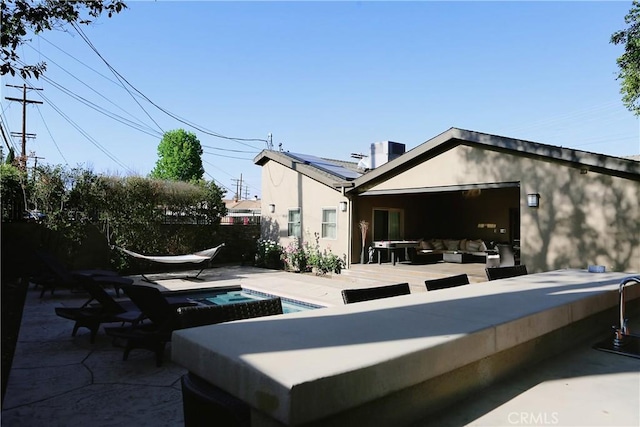 rear view of house with an outdoor living space, a patio, and a pool with hot tub