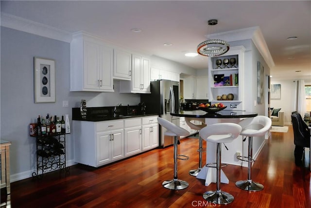 kitchen featuring white cabinetry, a breakfast bar, dark wood-type flooring, and ornamental molding