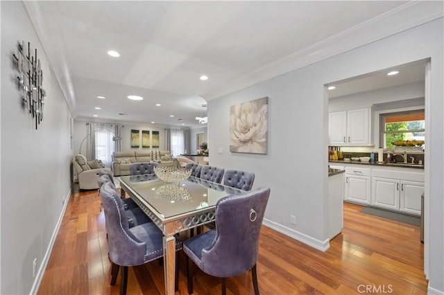 dining space with light hardwood / wood-style floors, ornamental molding, and sink