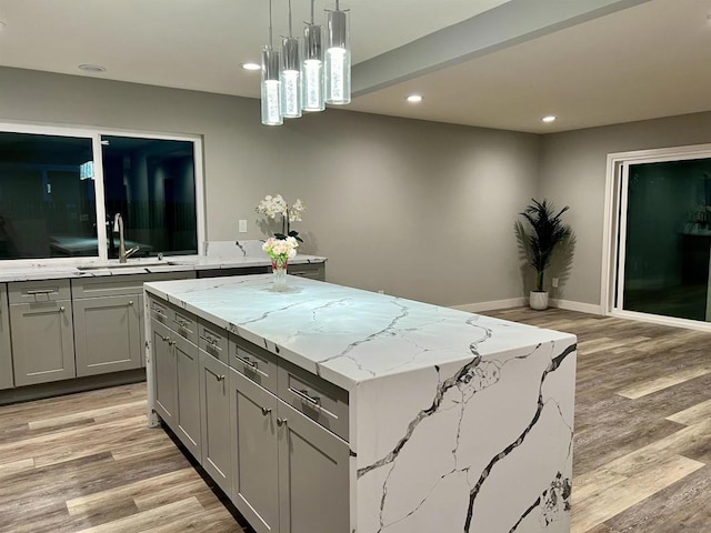 kitchen with gray cabinets, light hardwood / wood-style flooring, a center island, and sink