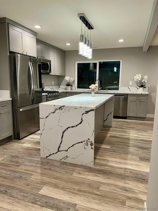 kitchen featuring gray cabinetry, light stone countertops, appliances with stainless steel finishes, and light hardwood / wood-style flooring