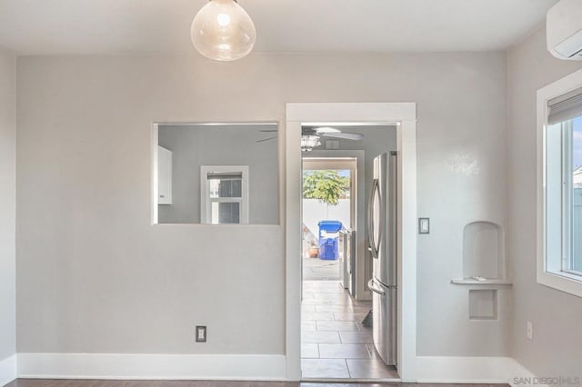 corridor with tile patterned flooring, an AC wall unit, and a wealth of natural light