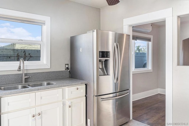 kitchen with stainless steel fridge, a healthy amount of sunlight, sink, and white cabinetry