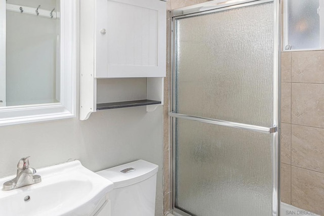 bathroom with an enclosed shower, toilet, and sink