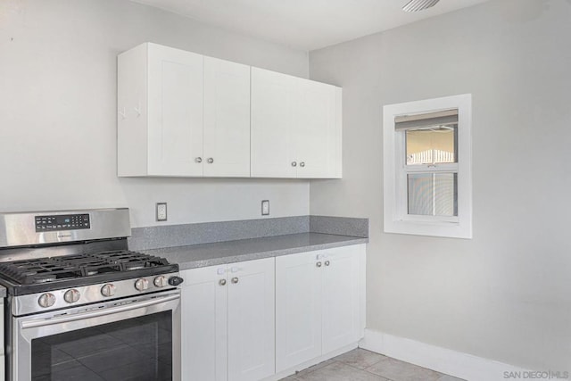 kitchen featuring white cabinets, light tile patterned flooring, and stainless steel gas range