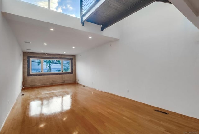 unfurnished living room with a towering ceiling and light hardwood / wood-style floors