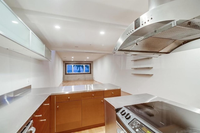 kitchen with light hardwood / wood-style floors, kitchen peninsula, exhaust hood, and stainless steel range