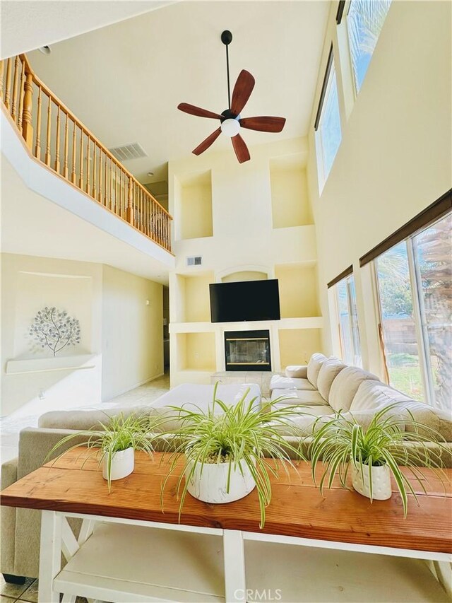 living room with ceiling fan, a towering ceiling, and a healthy amount of sunlight