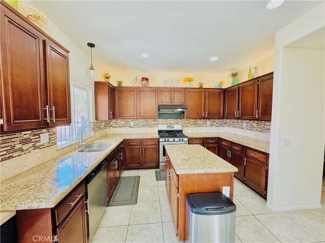 kitchen with light stone countertops, sink, hanging light fixtures, a kitchen island, and appliances with stainless steel finishes