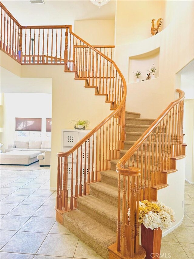 staircase with tile patterned floors and a high ceiling