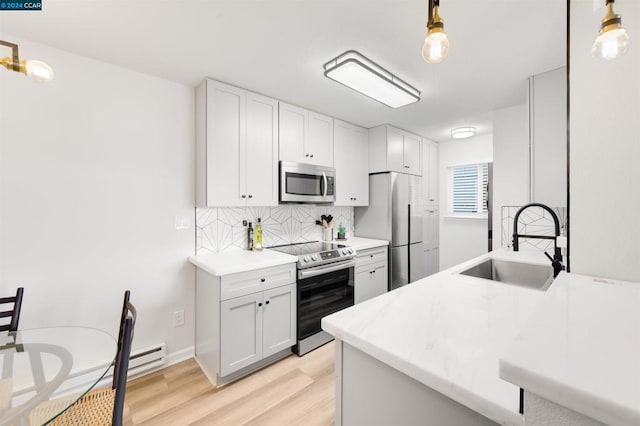 kitchen with sink, white cabinets, decorative light fixtures, and appliances with stainless steel finishes