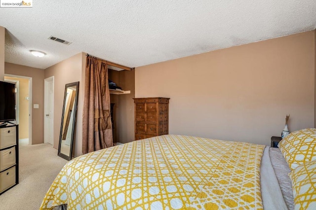 bedroom featuring light carpet and a textured ceiling